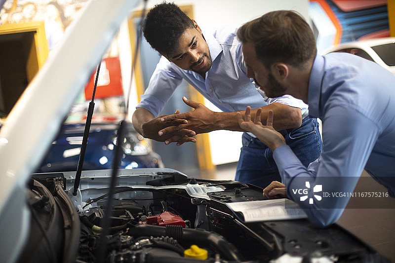 汽车销售员在汽车经销店向客户讲解新车性能图片素材