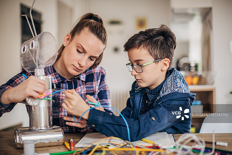 男孩和妹妹用回收材料为学校项目制作玩具图片素材