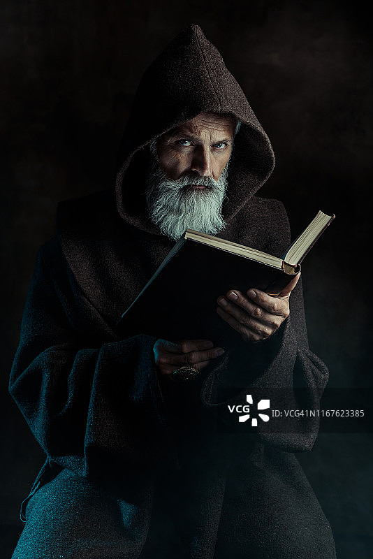 穿着传统服装拿着旧书的年长僧侣图片素材