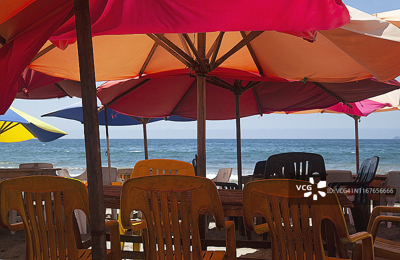 明亮的红色雨伞下的野餐桌和户外椅；墨西哥哈利斯科州Costalegre的Tenacatita湾图片素材