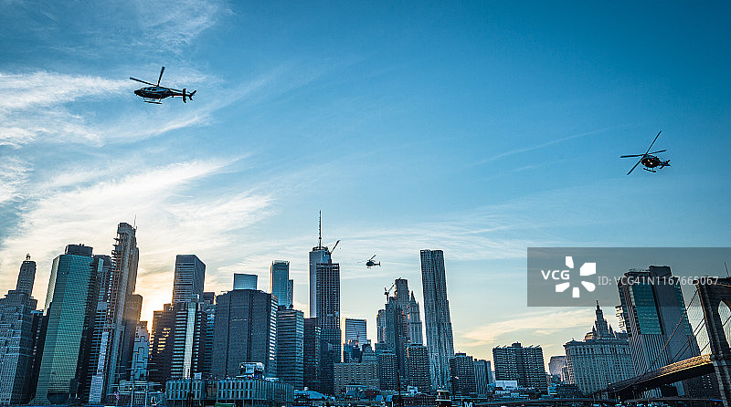 三架警用直升机在傍晚飞过纽约市曼哈顿金融区图片素材
