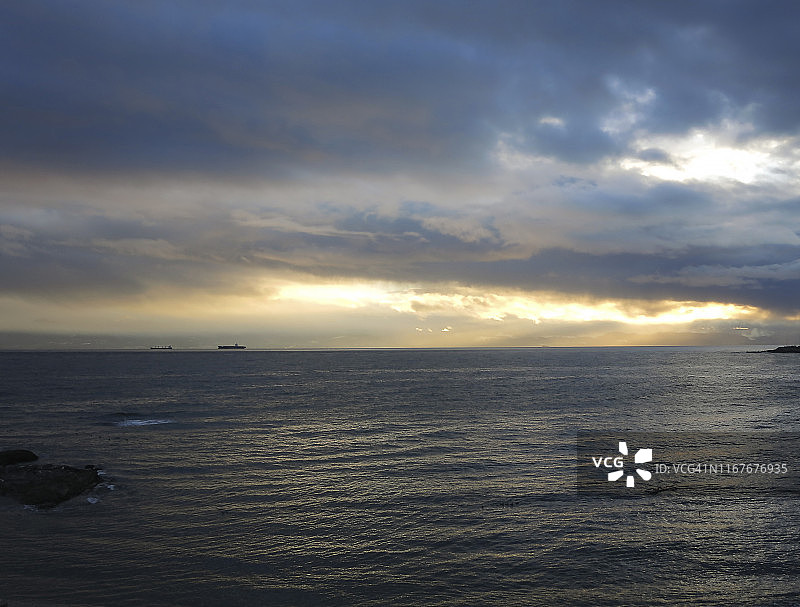 阴沉天空下地平线上的远处油轮图片素材