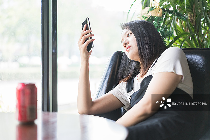 年轻女人在咖啡馆放松地使用智能手机图片素材
