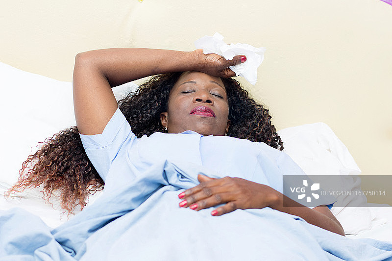 生病的非洲女人躺在床上，手里拿着白色手帕图片素材