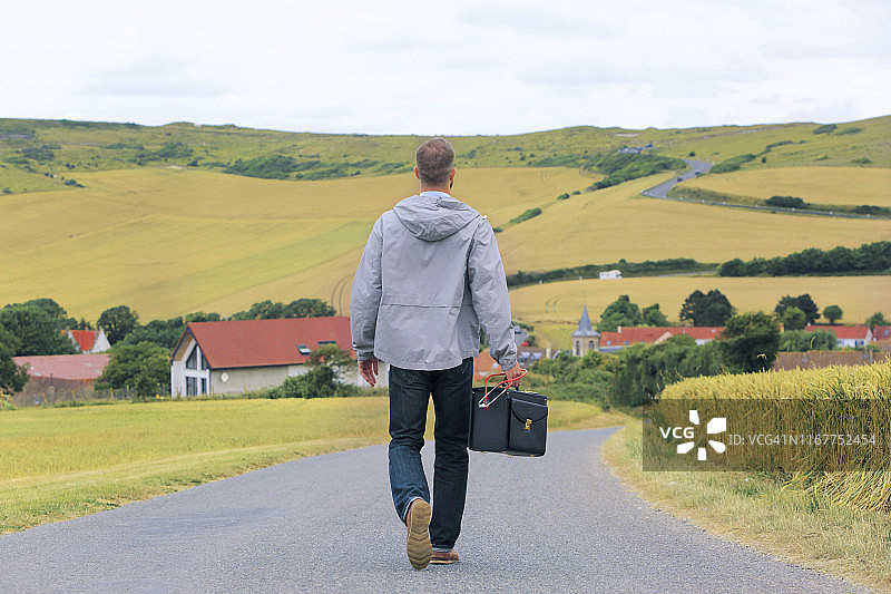 医学沙漠，一个年轻的医生回到一个乡村的道路上，一个村庄的背景图片素材