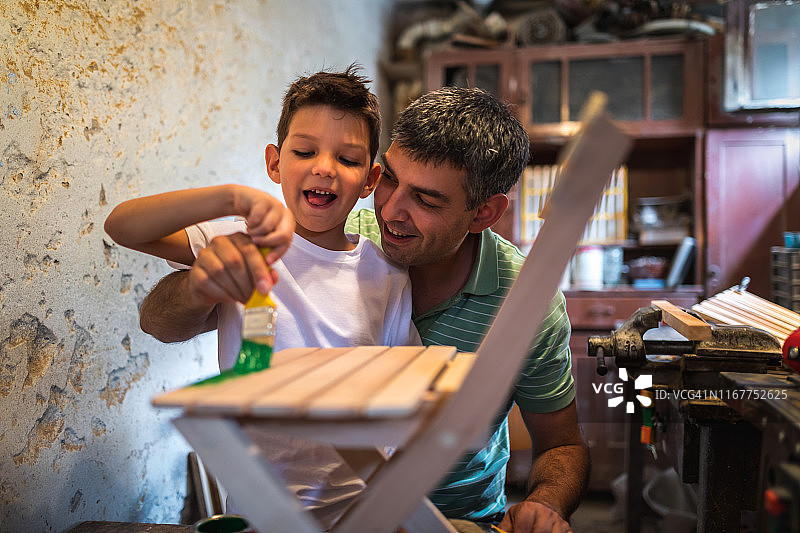 父子在工作室给椅子上色图片素材