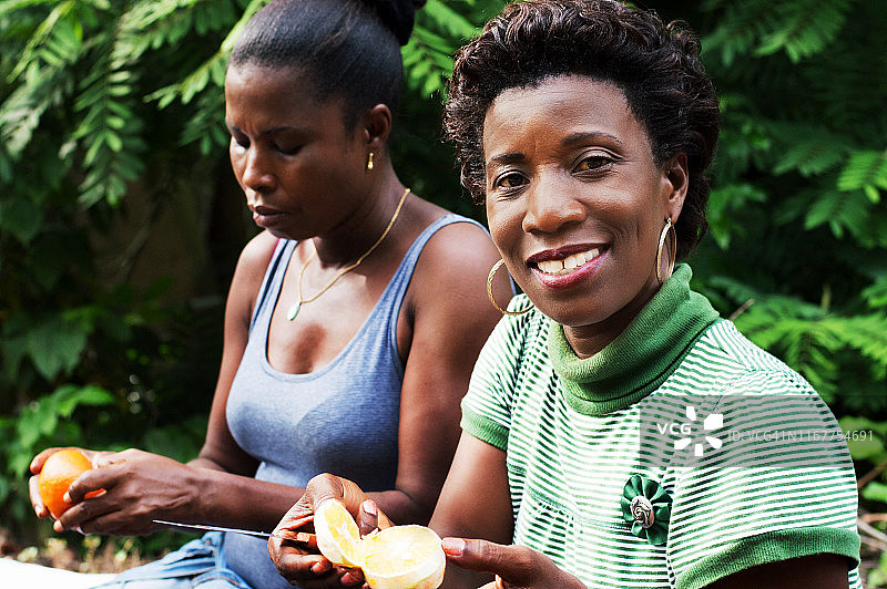 这位微笑的年轻女人正在切橙子图片素材