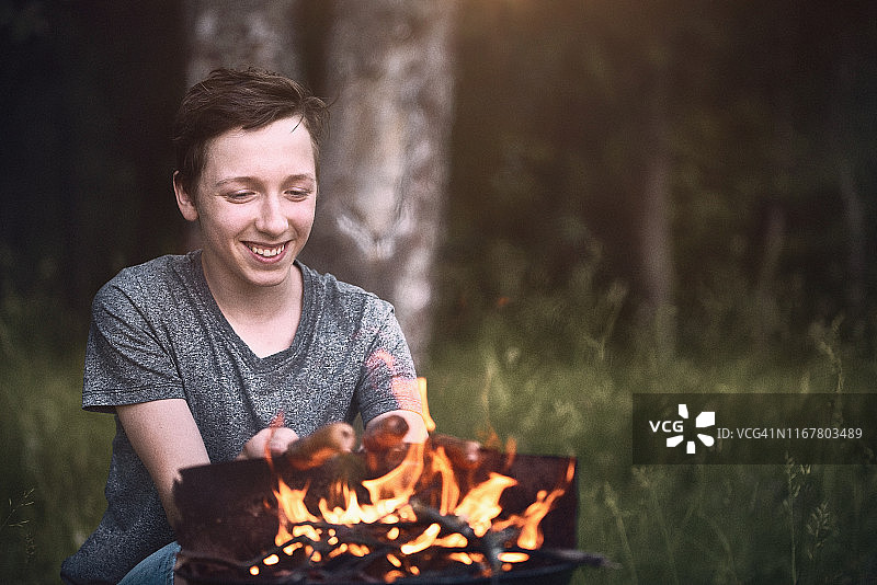 在烧烤架上烤香肠的少年图片素材