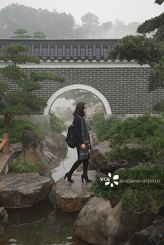 亚洲女人岩石小径行走，背景圆形拱门图片素材