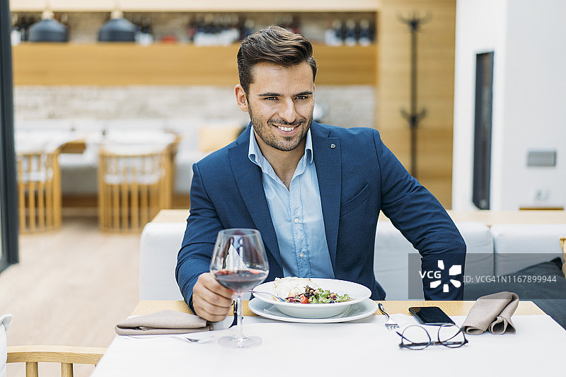 微笑男士在餐厅喝酒和吃东西图片素材