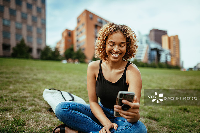 有着卷发的混血女人在户外午休时使用社交网络图片素材