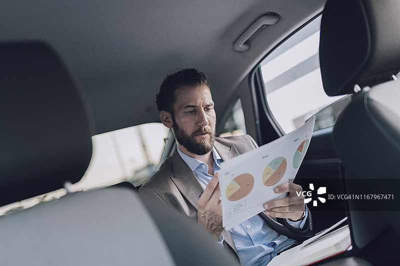 商务人士在汽车后座上拿着商业图表图片素材