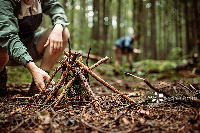 露营者在寒冷雨天于森林中生火取暖图片素材