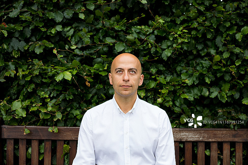坐在长椅上抬头看的中年秃顶男人图片素材