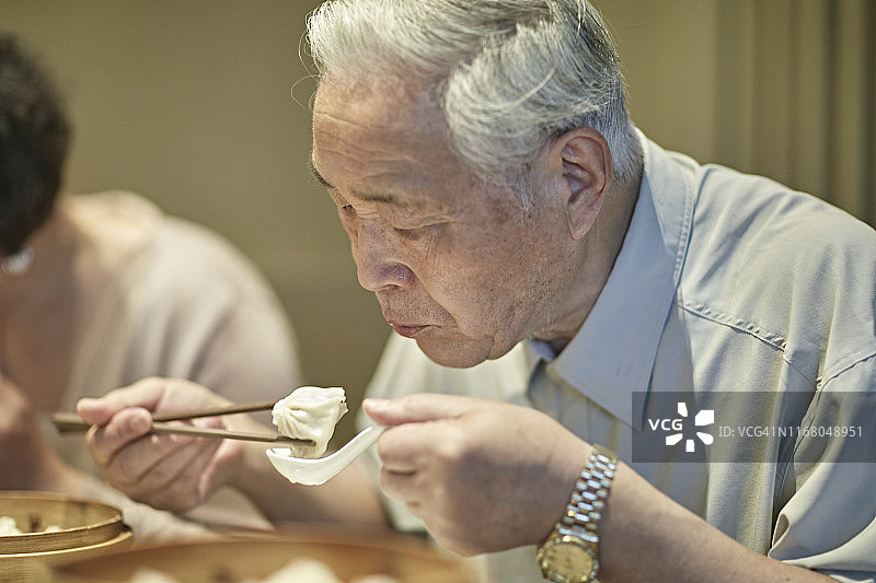 老年中国男人用筷子夹着饺子图片素材