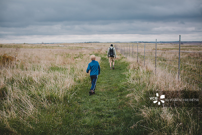 男人和男孩走在草原小路上图片素材