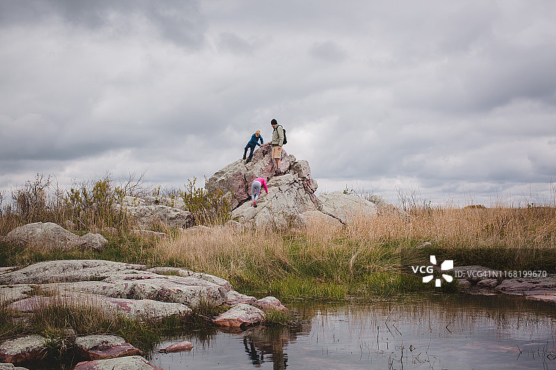 儿童与男人在草原岩石上攀爬图片素材