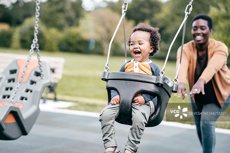 妈妈和蹒跚学步的孩子在操场上图片素材