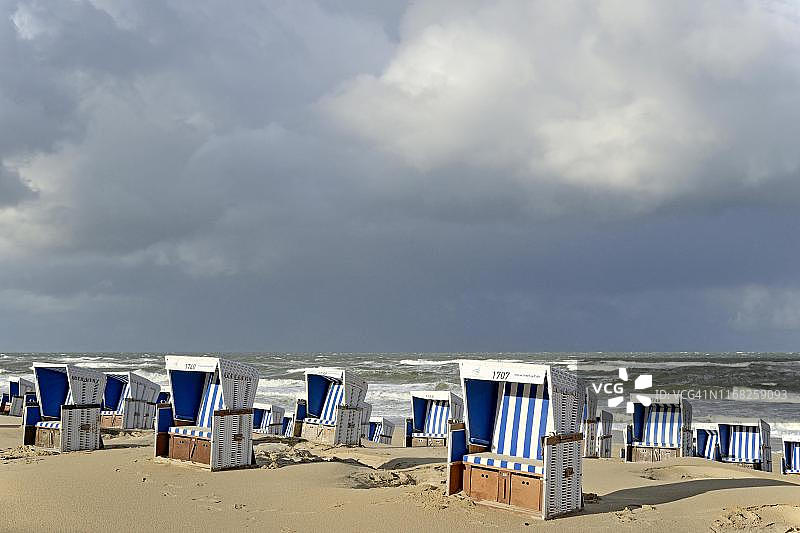 韦斯特兰海滩与沙滩椅及雨云，德国叙尔特岛图片素材