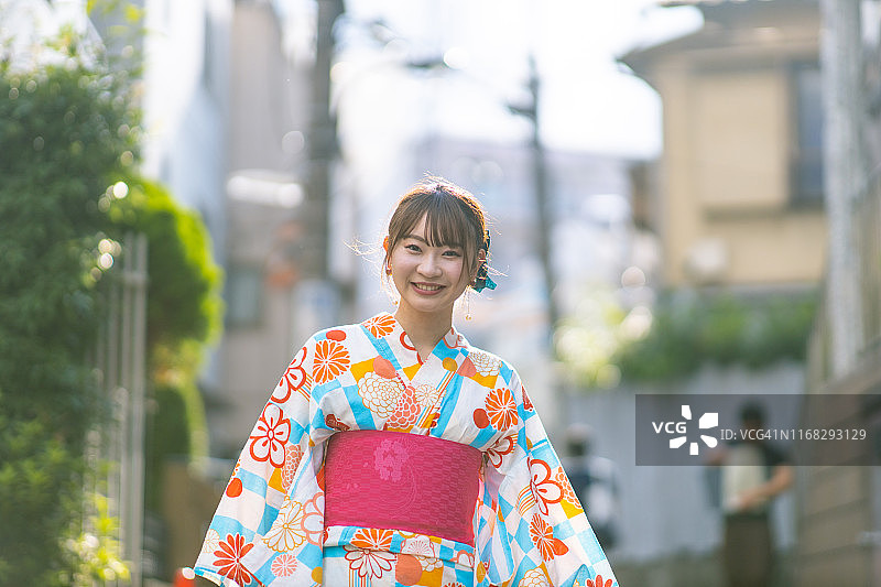 在日落时分走在街上的浴衣年轻女人图片素材