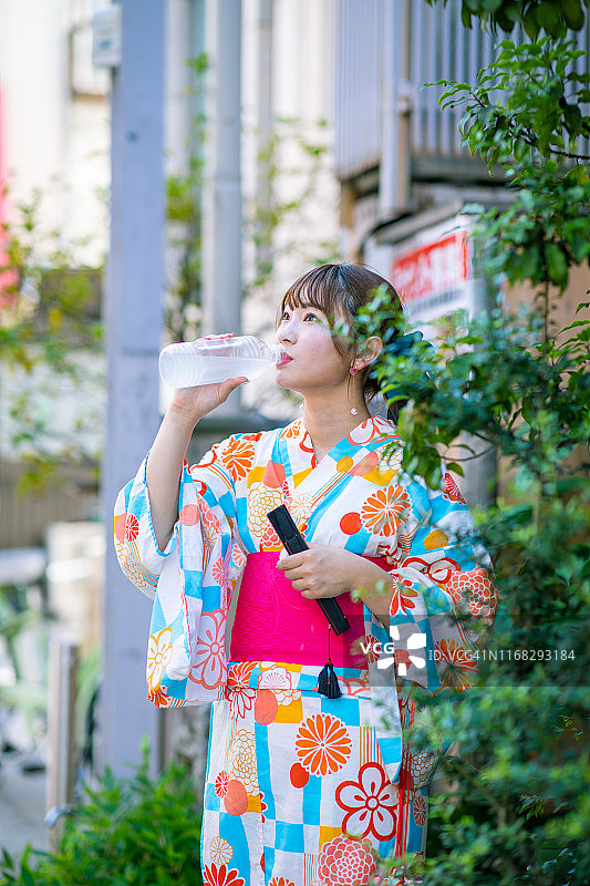 穿着浴衣的年轻女人在街上喝水图片素材