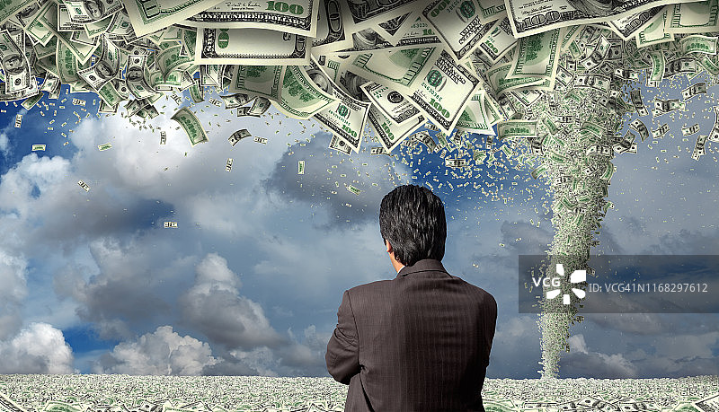 在金钱覆盖的景观上，观看金钱龙卷风的商人图片素材