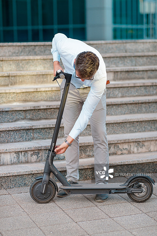年轻通勤者释放销子以折叠电动滑板车图片素材