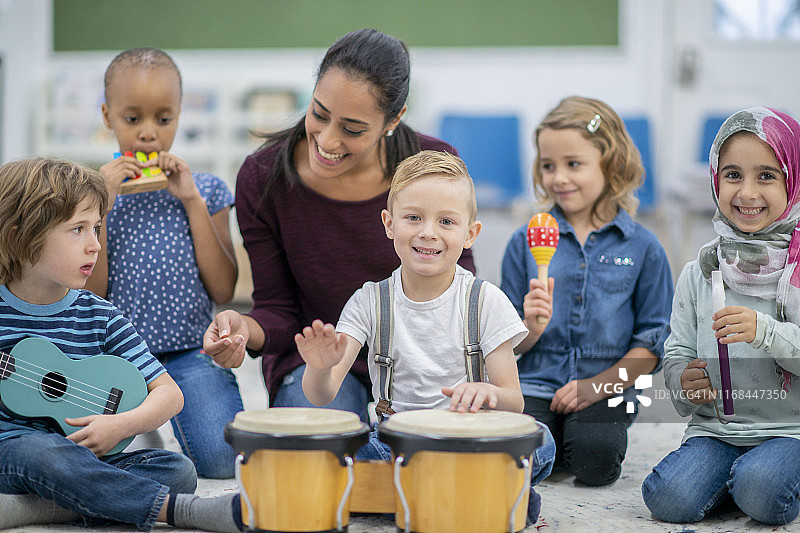 玩邦戈鼓并看着相机的男孩图片素材