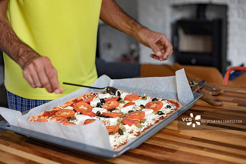 男人在自制披萨中添加食材图片素材