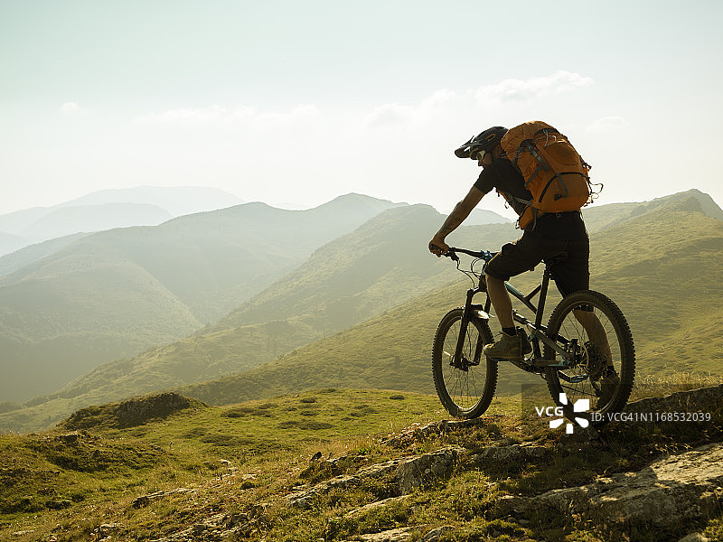 山地自行车手站在山顶上向前眺望图片素材