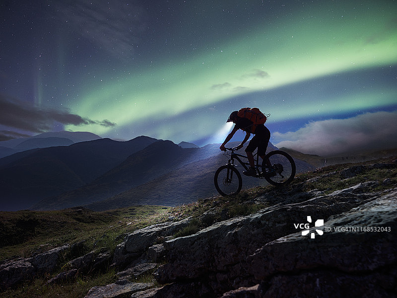 山地自行车骑行者在极光下的山区骑行图片素材