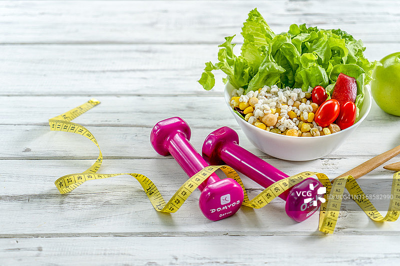 健身和节食的日记留白：健康生活方式概念。哑铃、蔬菜沙拉和卷尺在乡村木桌上。图片素材