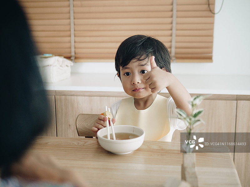 孙子在家和奶奶在桌上吃乌冬面图片素材