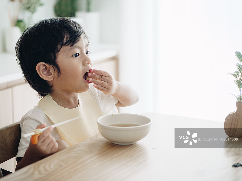 微笑的男童坐在高脚椅上吃饭图片素材