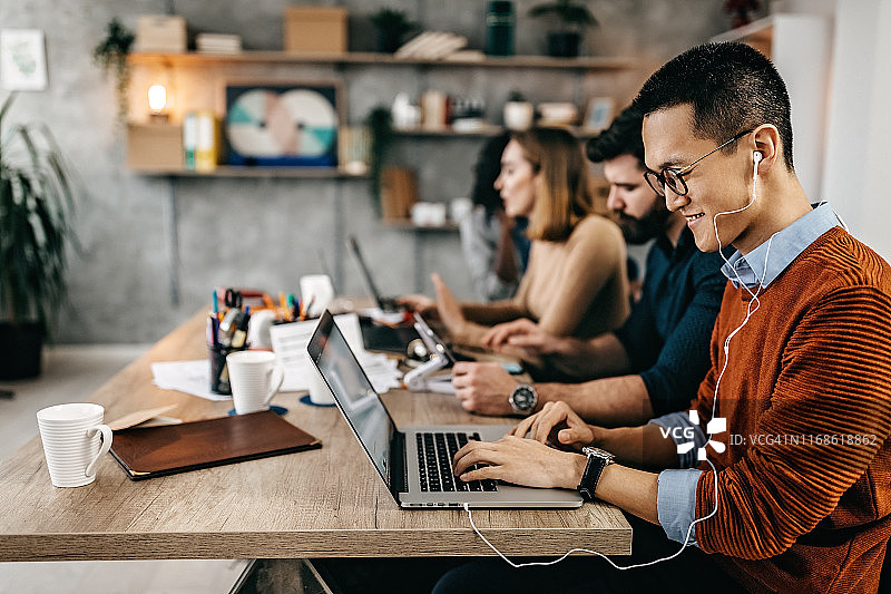 在现代办公室与同事一起工作的日本自由职业者图片素材