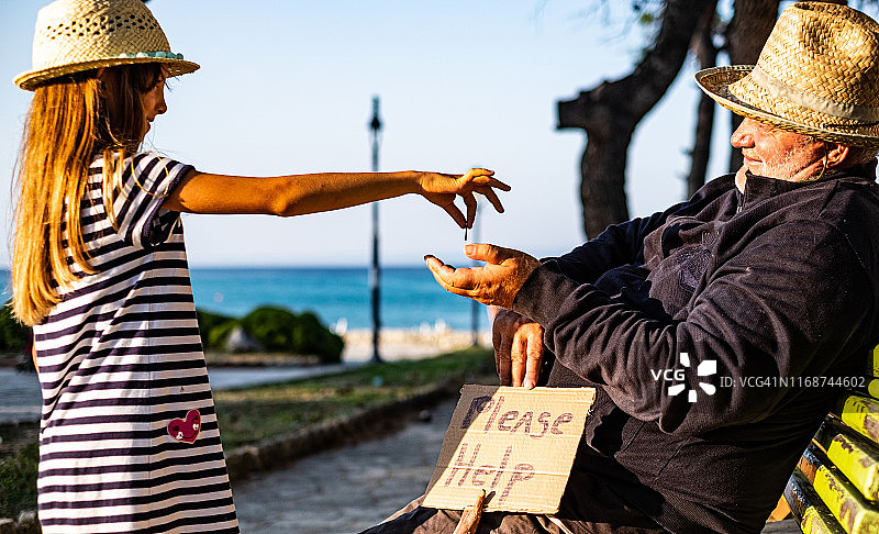 无家可归的男人从小女孩那里拿硬币图片素材