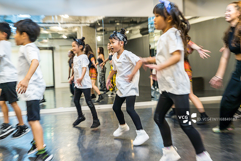 儿童舞蹈者在舞蹈工作室与年轻老师一起跳舞图片素材