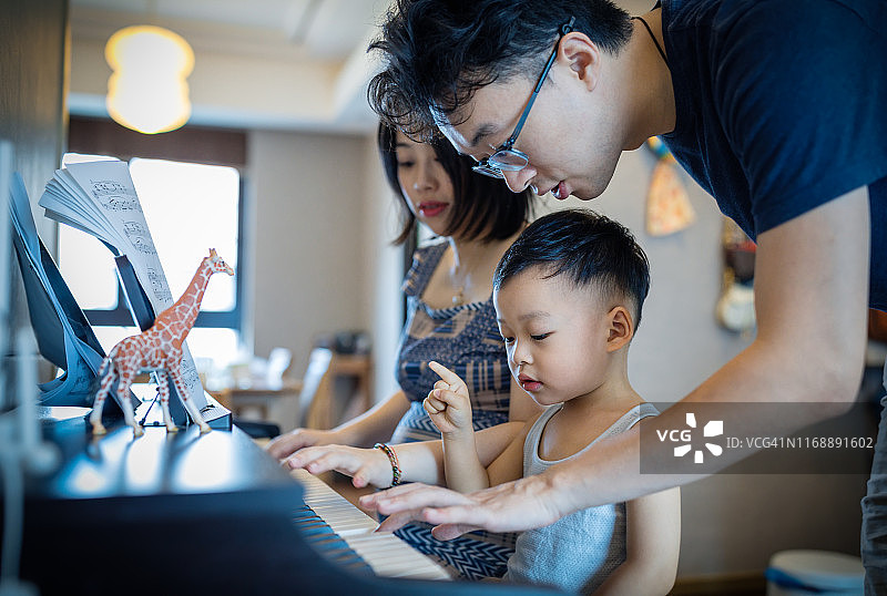 中国父母教儿子弹钢琴图片素材