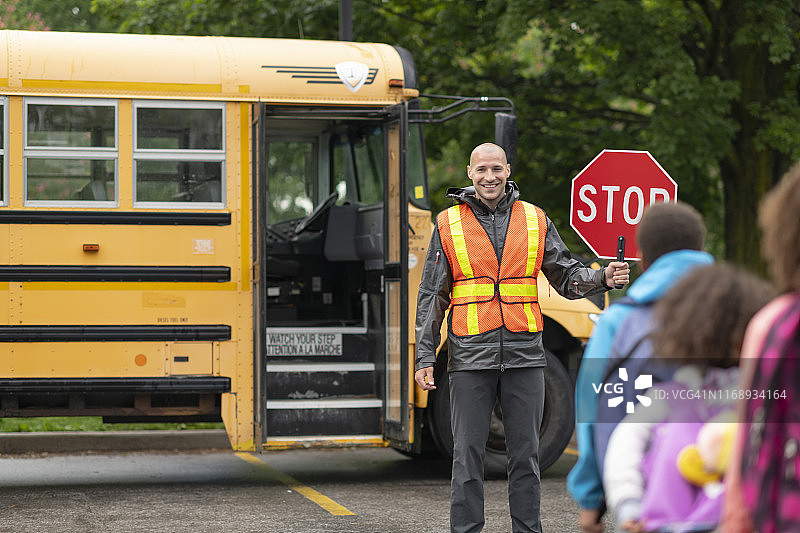 面带微笑的交通协管员帮助学生安全乘坐校车图片素材