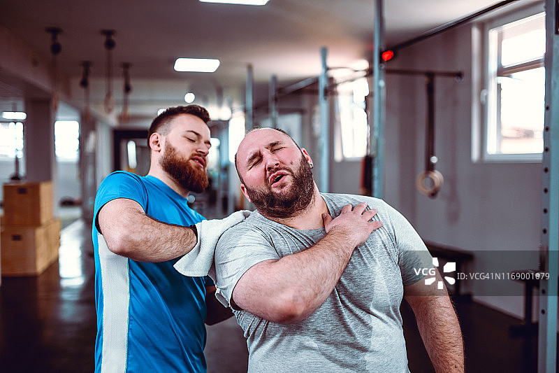 教练在艰苦的锻炼后按摩并帮助受伤的男性图片素材