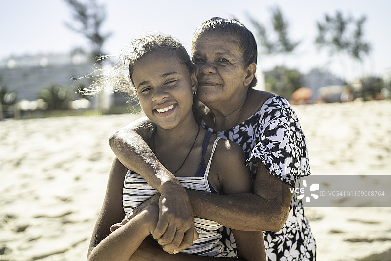 祖母与孙女在海滩拥抱的肖像照图片素材