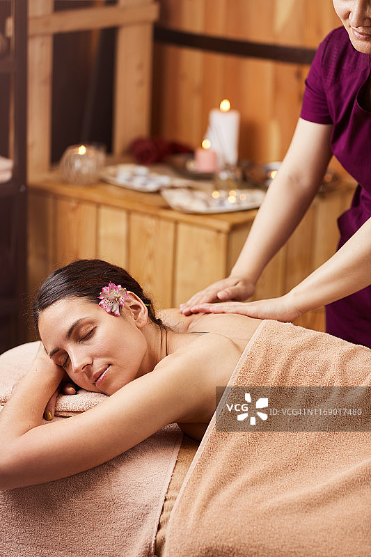 在水疗沙龙享受背部按摩的年轻女子图片素材