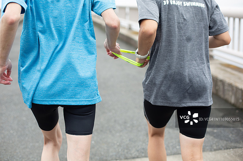 视障女性铁人三项运动员在引导下跑步图片素材