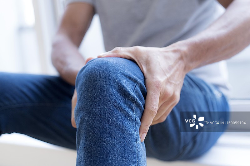 男人痛苦地按着左膝图片素材
