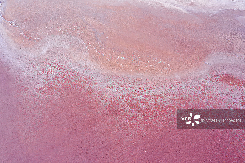 粉红色湖面上粉色、紫色和橙色的图案、纹理和惊艳色彩鸟瞰图片素材