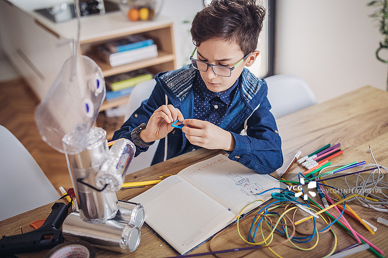 男孩为学校科学项目组装机器人图片素材