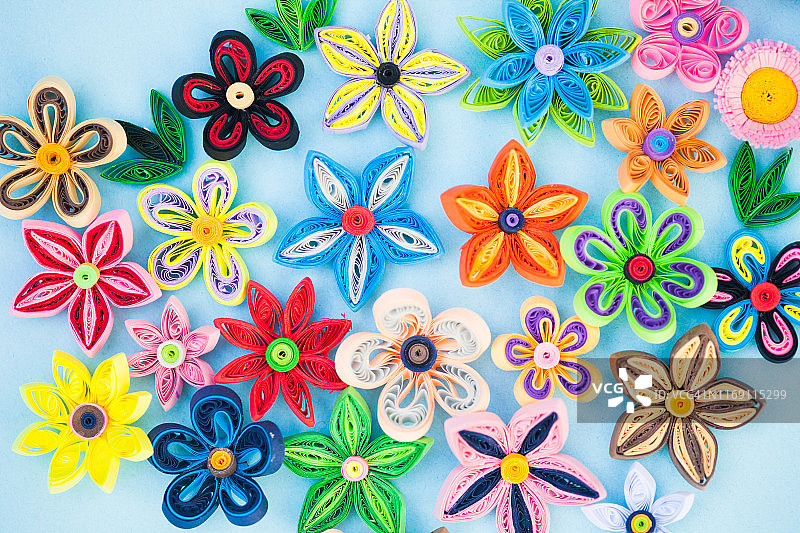 放置在青色背景上的彩色纸花图片素材