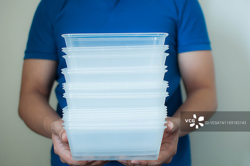 一名年轻男人在白色背景上拿着可回收的塑料食品容器图片素材