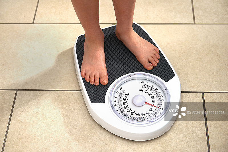 站在体重秤上的肥胖小男孩图片素材