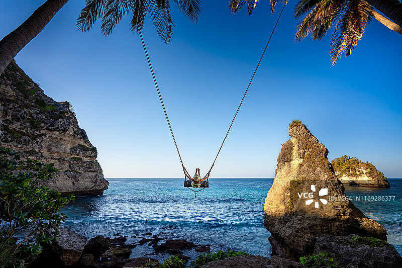 年轻女人在印度尼西亚努沙伯尼达岛荡秋千图片素材